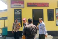 Haji Ramang Ishaka (topi merah) didampingi Kuasa hukumnya, Gabriel Kou (belakang), saat keluar dari ruang Unit Tipidum Polres Mabar, Kamis (30/4/2026) siang. [Foto Rino/GBRNews.id]