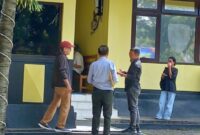 Haji Ramang Ishaka (topi merah) didampingi Kuasa hukumnya, Gabriel Kou (belakang), saat kembali masuk ke dalam ruang pemeriksaan Unit Tipidum Polres Mabar, Kamis (30/4/2026) siang. [Foto Rino/GBRNews.id]