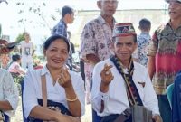 Roni Katu (kanan) didampingi istrinya, Fransiska Lidia (kiri), saat hadir di TPS dalam Pilkades Golo Ndoal, Selasa (29/9/2026). Foto: Rino/GBRNews.id