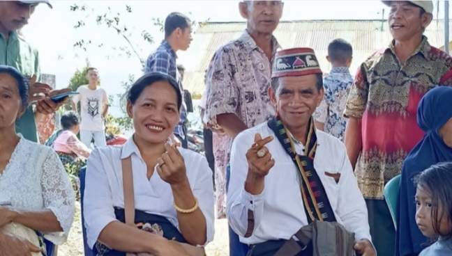 Roni Katu (kanan) didampingi istrinya, Fransiska Lidia (kiri), saat hadir di TPS dalam Pilkades Golo Ndoal, Selasa (29/9/2026). Foto: Rino/GBRNews.id